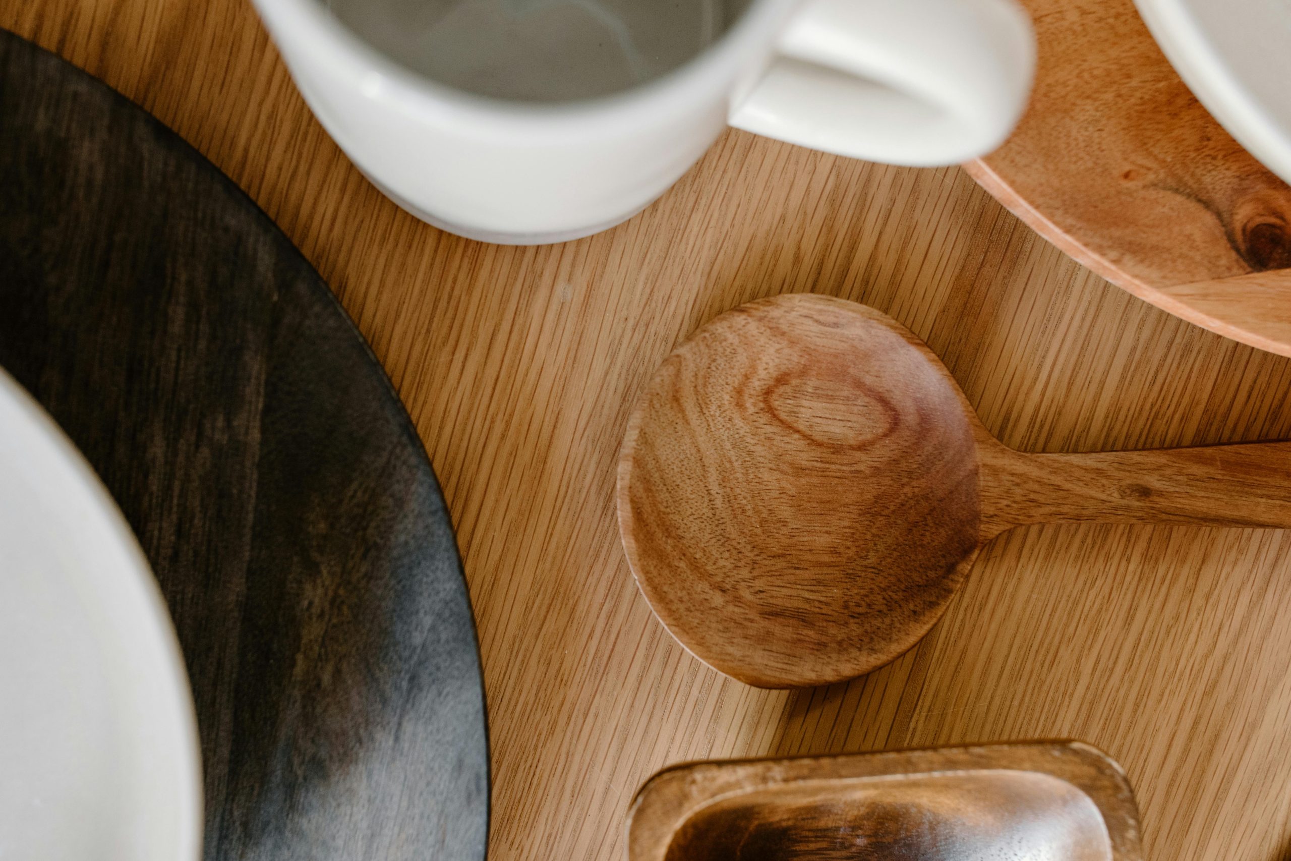 Wooden kitchen utensils on a minimalist table setting emphasizing Japandi style.