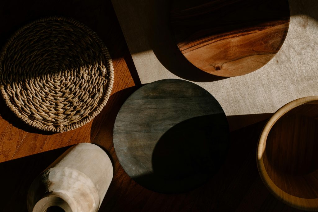 A flat lay of wooden kitchen utensils and woven materials in warm natural lighting, showcasing minimalist design.
