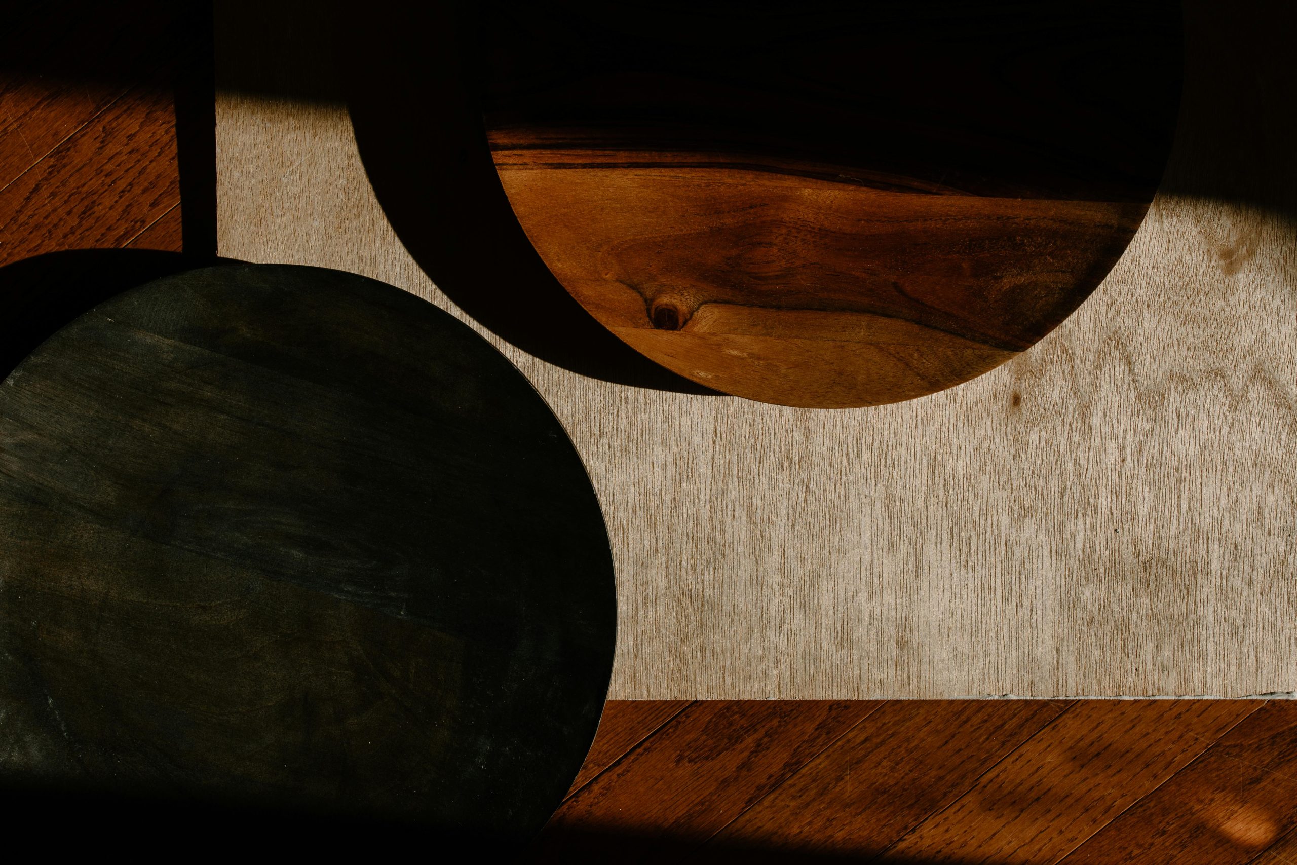 Minimalist wooden kitchenware casting artistic shadows on a rustic surface.